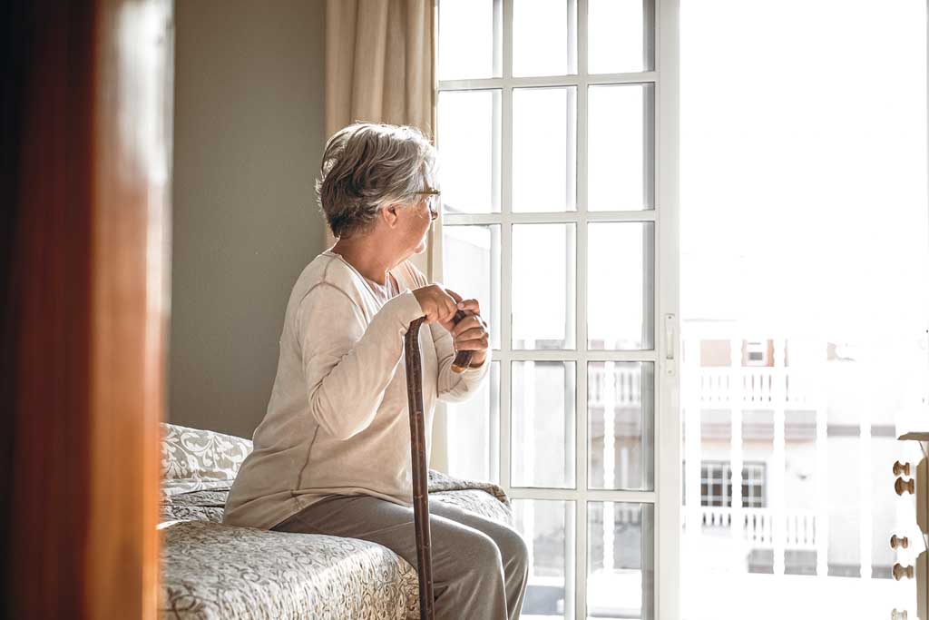 Thoughtful Senior Woman Leaning On Walking Stick While Sitting O